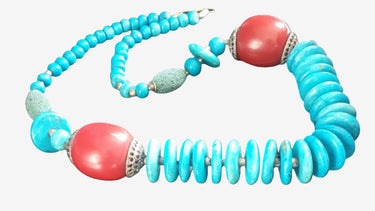 A vintage necklace with large amber-colored beads and smaller turquoise beads, some with a wooden appearance, strung together.