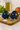 Two blue fish-shaped salt and pepper shakers on a wooden cutting board with a kitchen background.