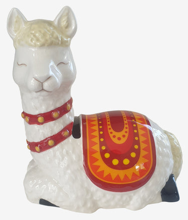 White ceramic llama figurine with red and yellow saddle blanket on a white background