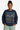 Person wearing a navy blue sweater with festive pattern on a beige background