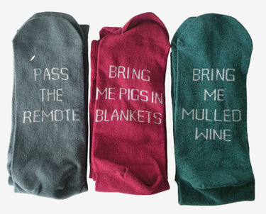 Three pairs of socks with humorous text designs on a light background