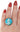 Ring with a blue and silver design on a hand with red nail polish against a white background