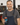 Man in a workshop wearing overalls and holding a can.