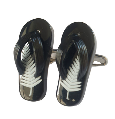 Black flip-flop cufflinks with white leaf design on a light wooden surface