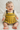 Baby wearing a yellow knitted dress with gray accents on a white background