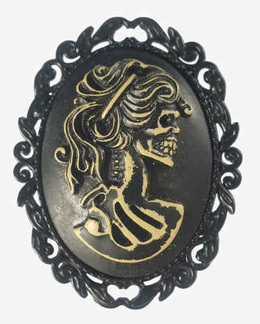 Decorative brooch with gold skeleton design on a black background