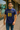 Man wearing a blue Lee Denim t-shirt with yellow text standing on a sidewalk.