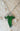 A green elven leaf necklace from The Lord of the Rings, displayed against a textured background.