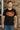 Man wearing a black t-shirt with a graphic design in front of a brick wall.