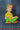 A enamel pin featuring the character Peter Pan from Disney's Peter Pan with a green outfit and red hair, sitting on a patch of blue denim.