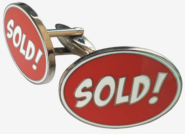 A pair of silver and red cufflinks with the word 'SOLD!' written in bold white letters on a red background.