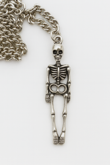 Silver skeleton pendant on a chain against a white background