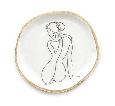 White dish with gold rim featuring a black line drawing of a woman on a white background