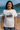 Woman wearing a white t-shirt with a graphic design on a beach. Planet Retro NZ.