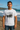 Man wearing a white t-shirt with a graphic design on a beach. Planet Retro NZ.