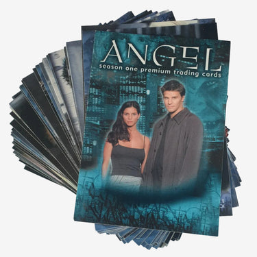 A stack of trading cards fanned out to show the front cover, titled 'ANGEL season one premium trading cards,' featuring a teal cityscape background and portraits of a man and woman.