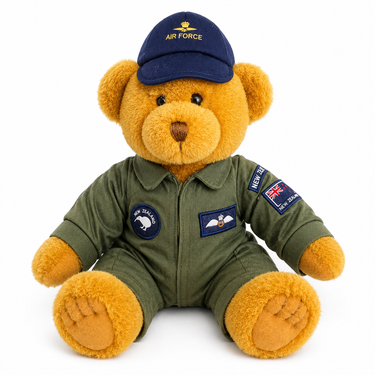 A plush teddy bear dressed as an Air Force pilot, wearing an olive green jumpsuit with patches and a navy blue cap with 'AIR FORCE' embroidered on it, photographed against a solid white background.