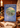 Book titled 'Bilbo's Last Song' by J.R.R. Tolkien on a wooden surface with candles and books in the background.