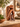Carved suar wood resting man sculpture styled on a stone console with pottery and leafy plants in a warm neutral interior