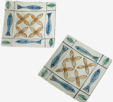 Two ceramic tiles with fish and flower patterns on a white background