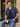 Man wearing Harry Potter navy constellation shirt open over navy V-neck T-shirt, seated outdoors with coffee