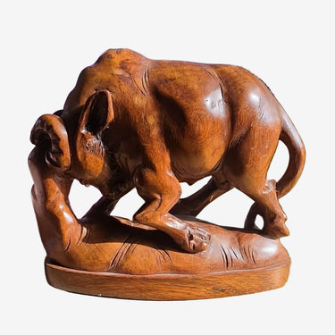 A carved wooden sculpture of a muscular bull standing on a base.