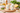 Two ceramic salt shakers with colorful polka dots on a wooden cutting board with herbs and a lemon.