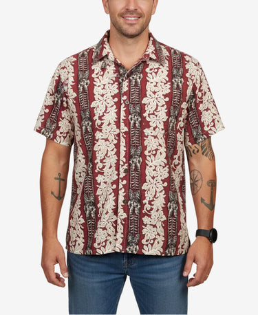 Mens crimson tropical Hawaiian style shirt with cream floral panels and tribal-style details, shown on a male model with jeans.