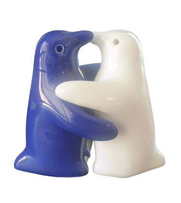 A ceramic salt shaker featuring a blue penguin hugging a white penguin on a white background