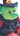 Green plush toy with black hair and red outfit on a blurred background