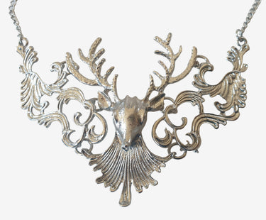 Silver deer head necklace on a light gray background
