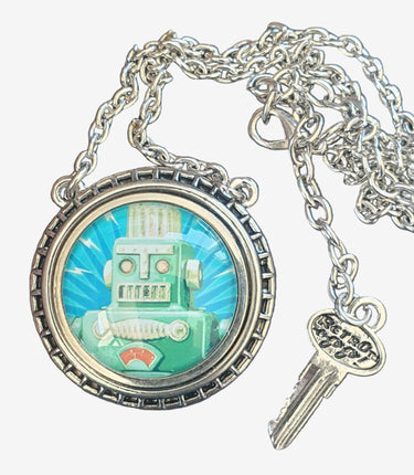 Necklace with a round pendant featuring a robot design on a grey surface.