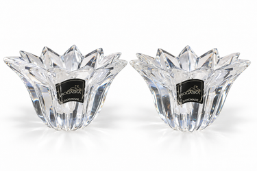 Two clear faceted crystal candleholders with a flower-like petal design and black square labels reading Handmade by Rogaska, shown on a white background.