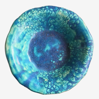 A handmade ceramic bowl with a marbled blue and green glaze.