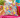 Colourful Sugar Skulls & Birds handmade cushion cover styled on wicker chair with bright pink throw and plants