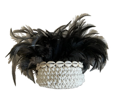Decorative woven basket with black feathers and shell trim styled as sculptural home décor