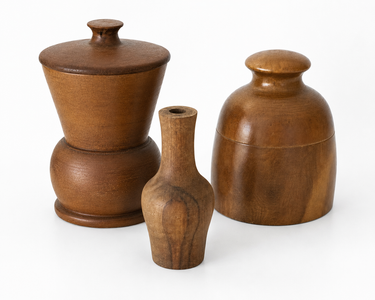 Set of three turned wooden vessels in warm brown timber tones, including two lidded pots and a small bud vase.