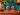 Pair of small vintage Balinese carved wooden busts styled on a wooden cabinet against a teal blue wall