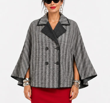A woman modeling a gray and black patterned cape jacket with black trim, paired with a red pencil skirt and black heels, against a plain light gray studio background.