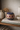 Decorative ceramic vase with a geometric pattern on a shelf with books and other items.