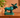 Vintage green glazed ceramic moose figurine displayed on a mid-century wooden sideboard against a soft terracotta wall with a leafy houseplant