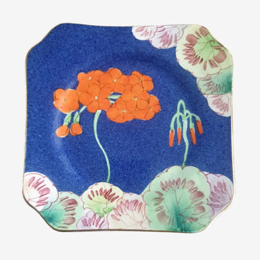 Vintage Japanese square side plate with cobalt blue background, orange floral design and gold rim, displayed on stand
