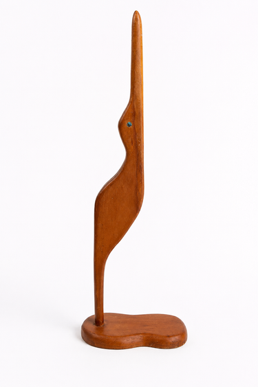 Vintage 1970s wooden bird sculpture with paua shell detail, side view on light grey studio background.