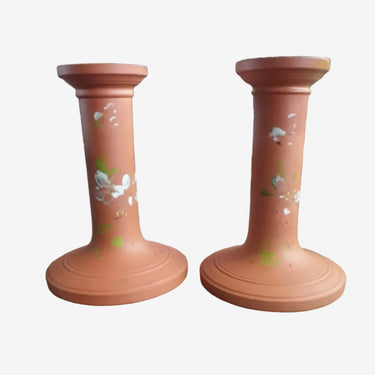 Pair of vintage Watcombe Torquay terracotta candlestick holders with hand-painted white floral design, 14cm tall.