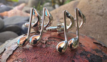 Silver musical note cufflinks on a textured surface