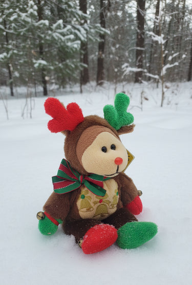 Plush reindeer toy in a snowy forest setting