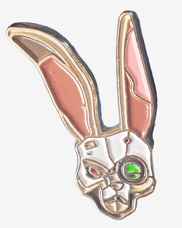 An enamel pin depicting a stylized bunny mask with pink details and green eyes, attached to a denim fabric.