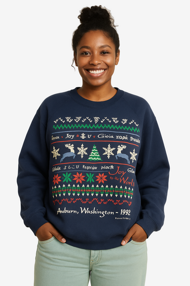 Person wearing a navy blue sweater with festive pattern on a beige background