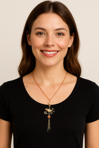 Woman wearing a black shirt with a decorative necklace against a plain background
