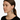Woman wearing a decorative earring on a plain background